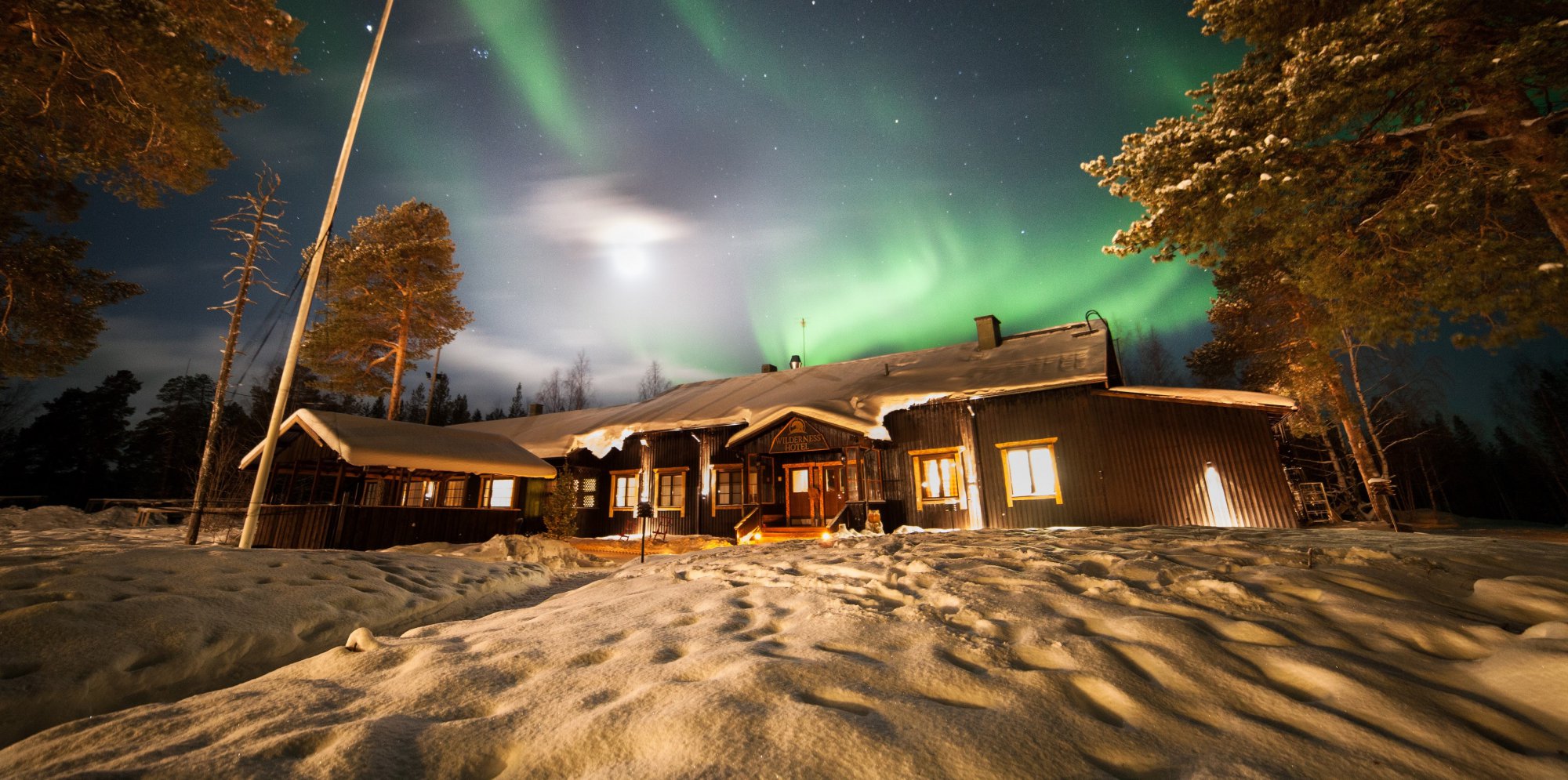 Nellim Wilderness Hotel main building with northern lights above it