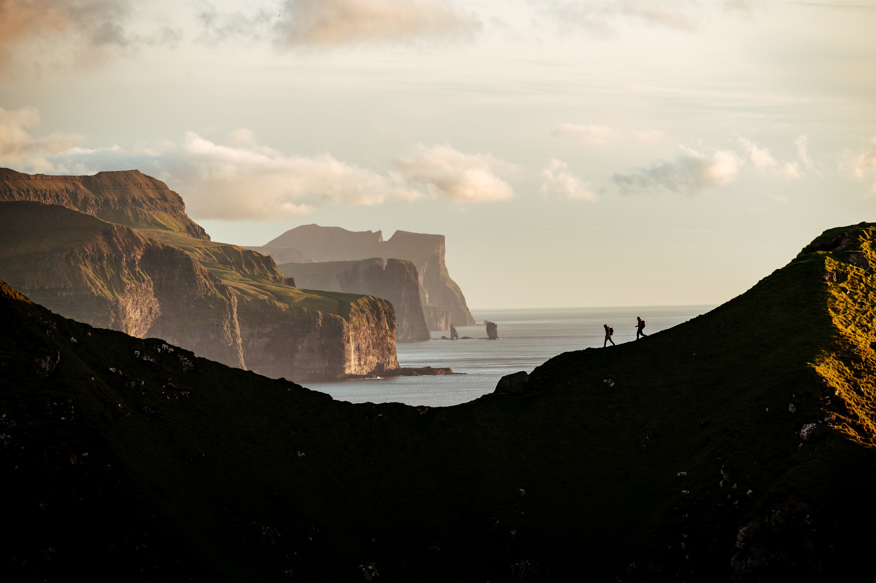 Two people hiking on a ridge of a mountain in the Faroe Islands