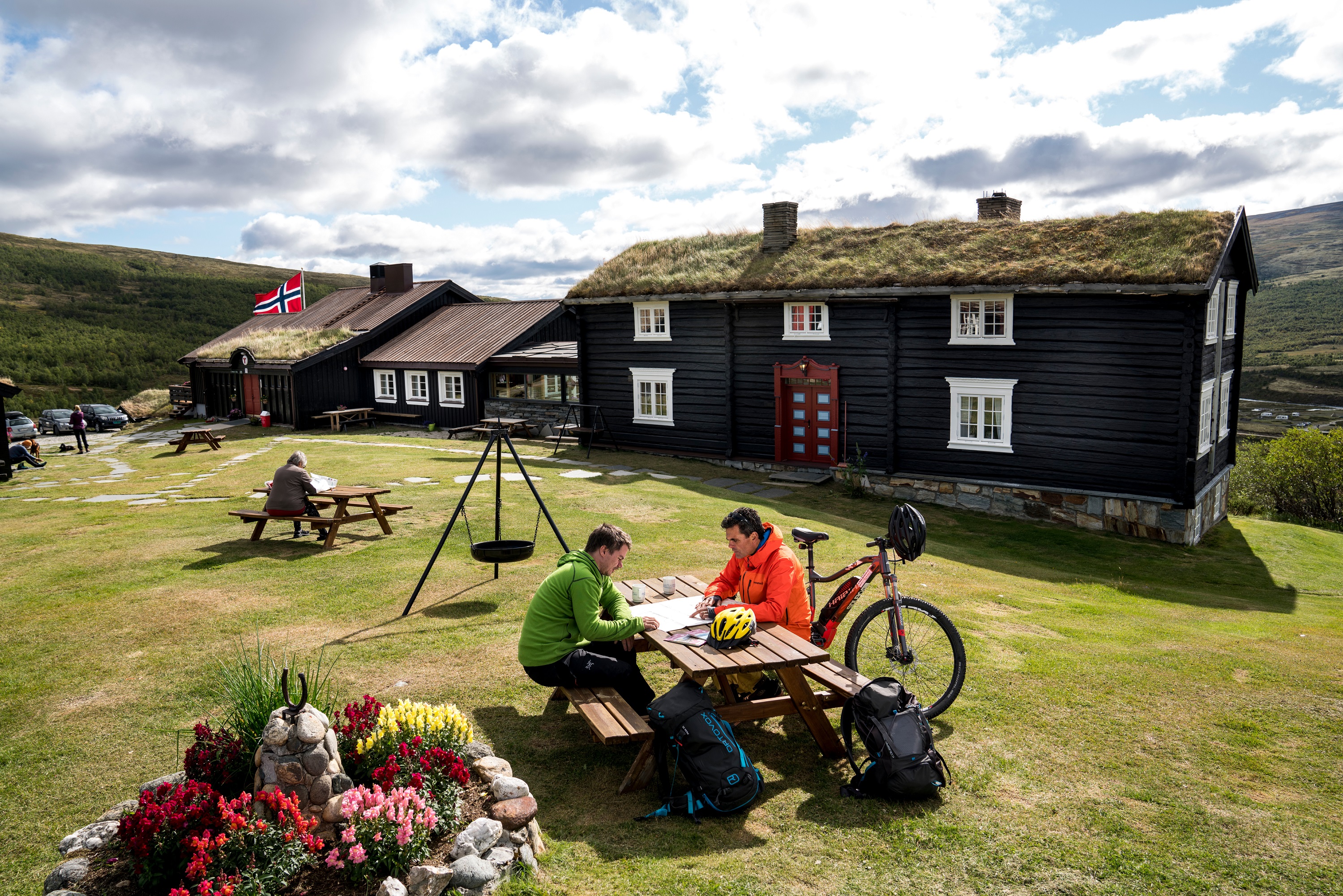 Cyclists planning their trip at a table outside Grimsdalshytta Lodge in Norway